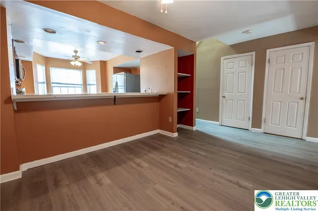 a view of an empty room with wooden floor and a window