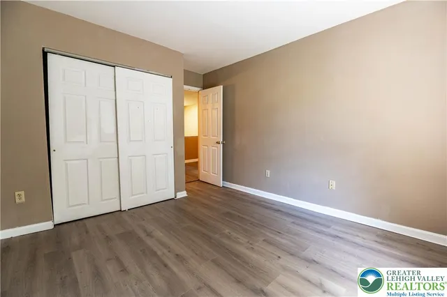 a view of an empty room with closet and wooden floor