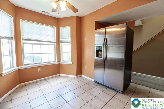a view of an empty room with window and chandelier fan