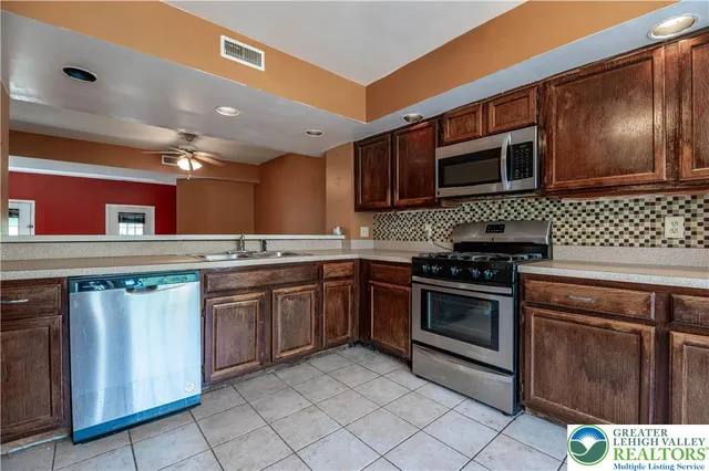 a kitchen with stainless steel appliances granite countertop a stove a sink and a microwave