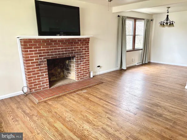 an empty room with wooden floor fireplace and windows