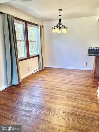 a view of an empty room with chandelier and wooden floor