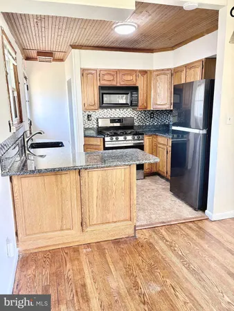 a kitchen with granite countertop a refrigerator and a stove top oven