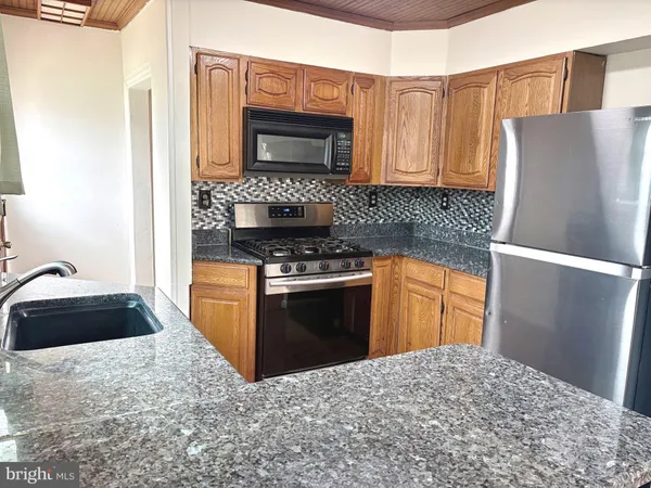 a kitchen with granite countertop a refrigerator stove and sink