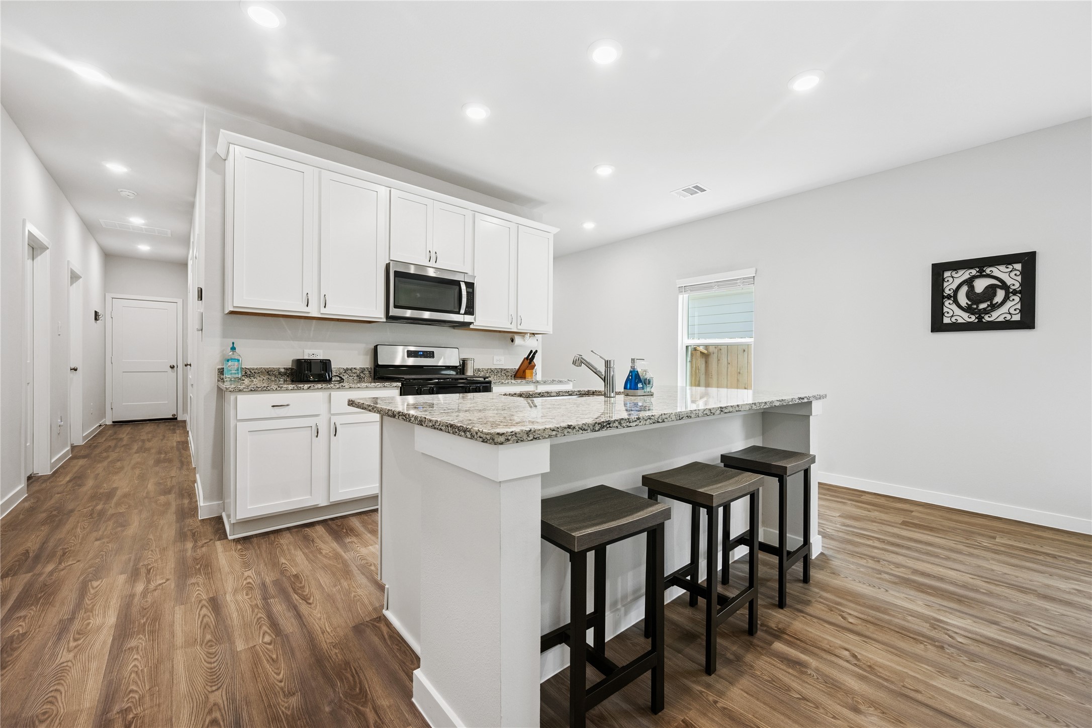 16934 Needlepoint Drive Conroe, TX 77302 - Photo 6 of 24 a kitchen with granite countertop white cabinets and black stainless steel appliances