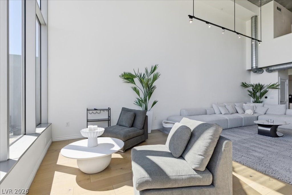 360 East Desert Inn Road, Unit 604 Las Vegas, NV 89109 - Photo 22 of 28 Natural light drenches this living space, highlighting its sleek hardwood flooring and soaring high ceilings.