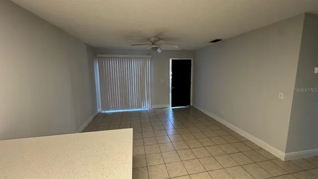 an empty room with an entryway and chandelier fan