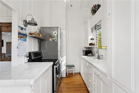 a kitchen with a sink dishwasher a stove and a refrigerator with wooden floor