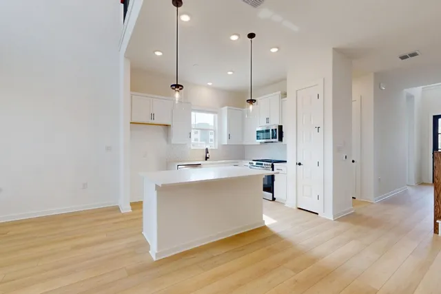 a large kitchen with stainless steel appliances kitchen island a large counter top and a sink