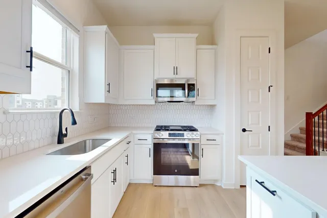 a kitchen with cabinets appliances a sink and a window