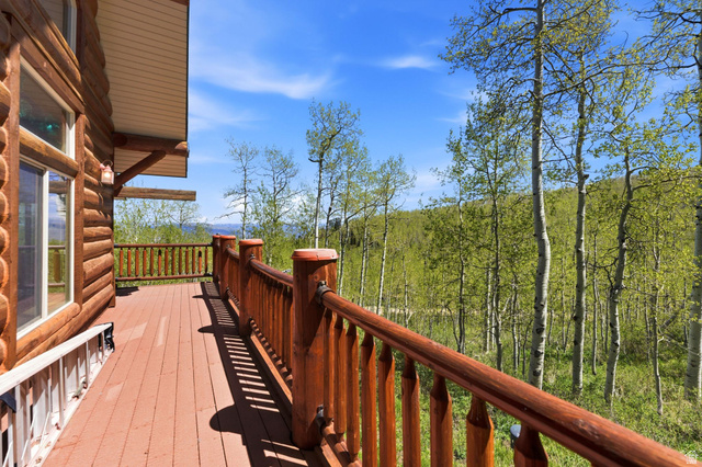 2096 South Aspen Ridge Coalville, UT 84017 - Photo 32 of 44 Expansive log-sided deck featuring a wood railing and a natural tree-lined backdrop