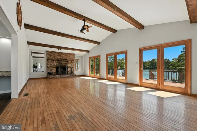 a view of an empty room with wooden floor and a fireplace