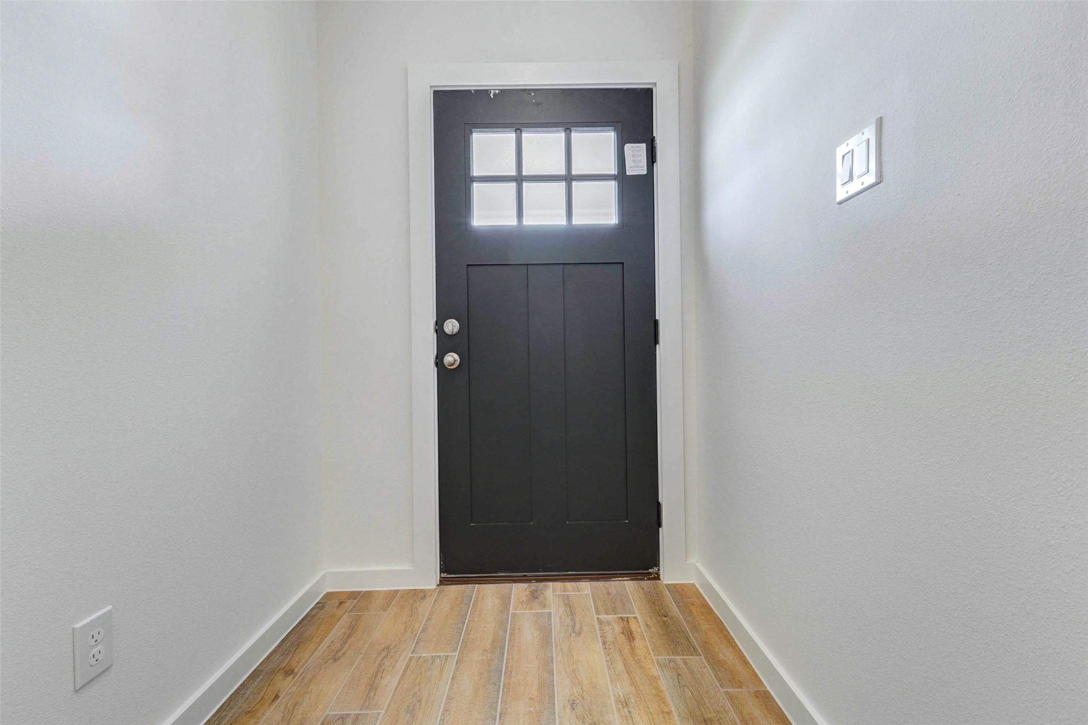 6475 Escondido Drive Rosharon, TX 77583 - Photo 10 of 32 Step inside to a bright entryway featuring a black front door, wood-look tile flooring, and clean white walls. The compact foyer feels fresh and functional, offering a crisp first impression with natural light from the door’s window panels and a neutral design ready for personal touches.