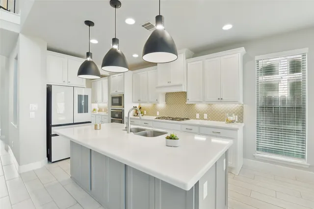 a large kitchen with sink a refrigerator and chairs