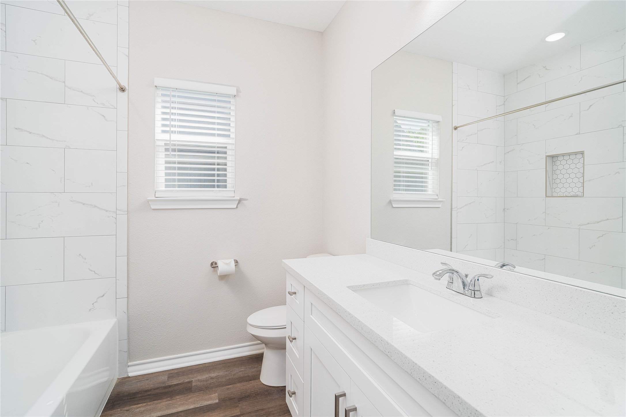 231 McCormick Street Columbus, TX 78934 - Photo 21 of 27 Bathroom – Full bath showcasing a quartz countertop, large mirror, and a tiled tub/shower combination with a built-in niche.