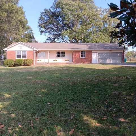 a view of a yard in front of a house with large trees