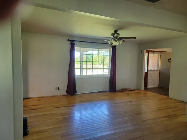 a view of an empty room with window and wooden floor