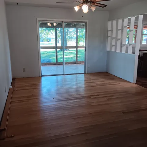 an empty room with wooden floor and windows
