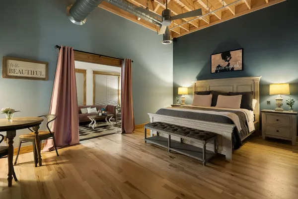 a bedroom with a bed a chair and potted plant on the table