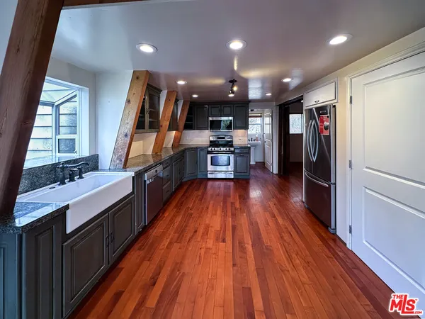 a large open kitchen with a large window a sink and stainless steel appliances