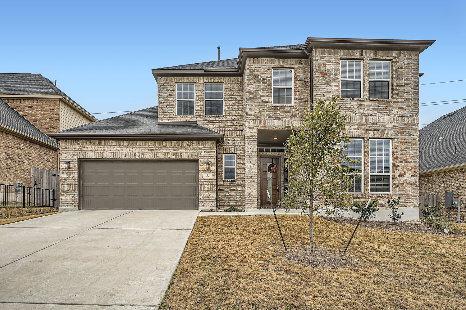View of front of house featuring driveway, brick siding, roof with shingles, and a garage
