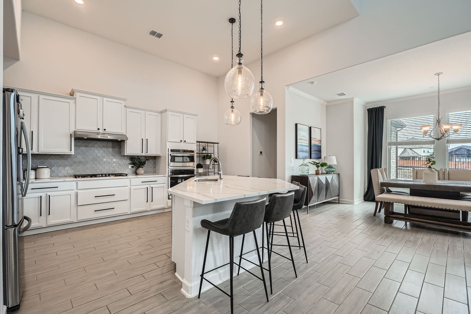 582 Wild Pecan Loop Buda, TX 78610 - Photo 11 of 28 Kitchen featuring wood tiled floors, decorative backsplash, a kitchen bar, white cabinetry, and an island with sink