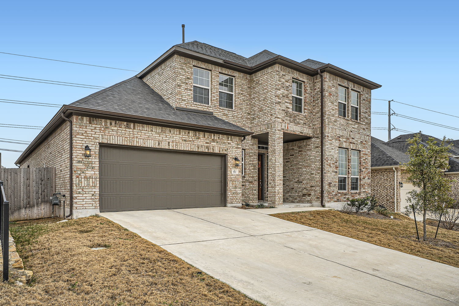 582 Wild Pecan Loop Buda, TX 78610 - Photo 2 of 28 View of front facade featuring brick siding, concrete driveway, roof with shingles, and an attached garage