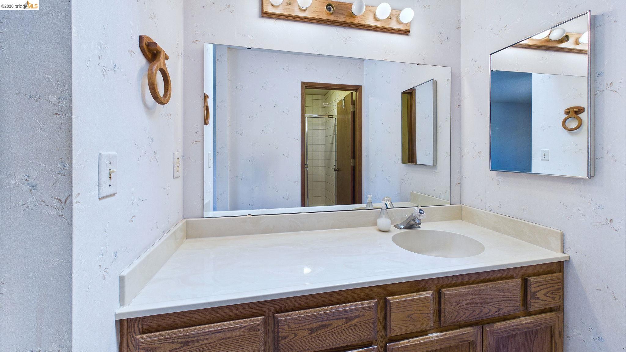 23686 Marble Quarry Road, Unit 72 Columbia, CA 95310 - Photo 23 of 35 Single basin vanity with wood-finish cabinetry, integrated sink, and wall-mounted mirror