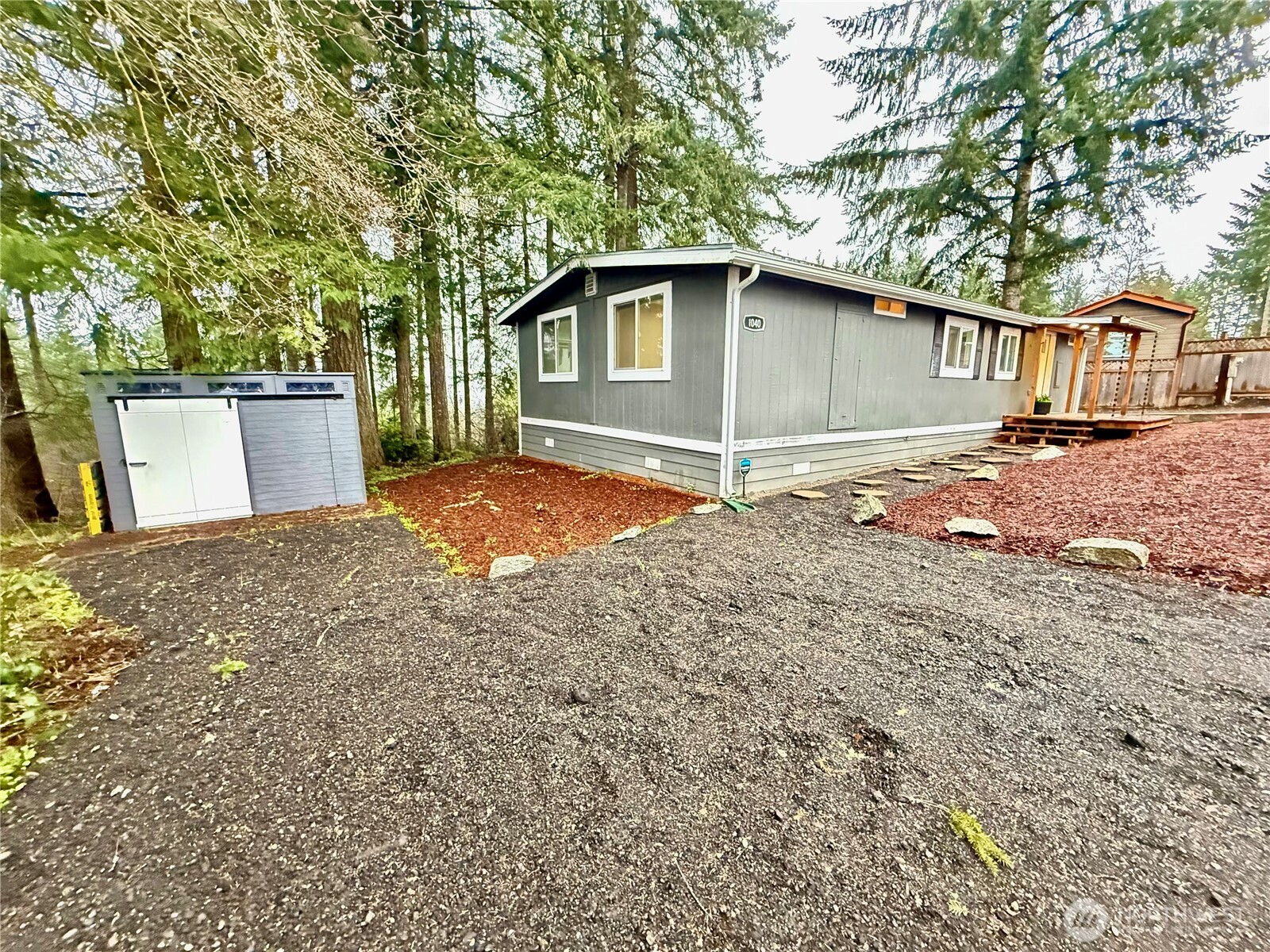 1040 Northeast Larson Boulevard Belfair, WA 98528 - Photo 3 of 18 a backyard of a house with wooden fence and large trees