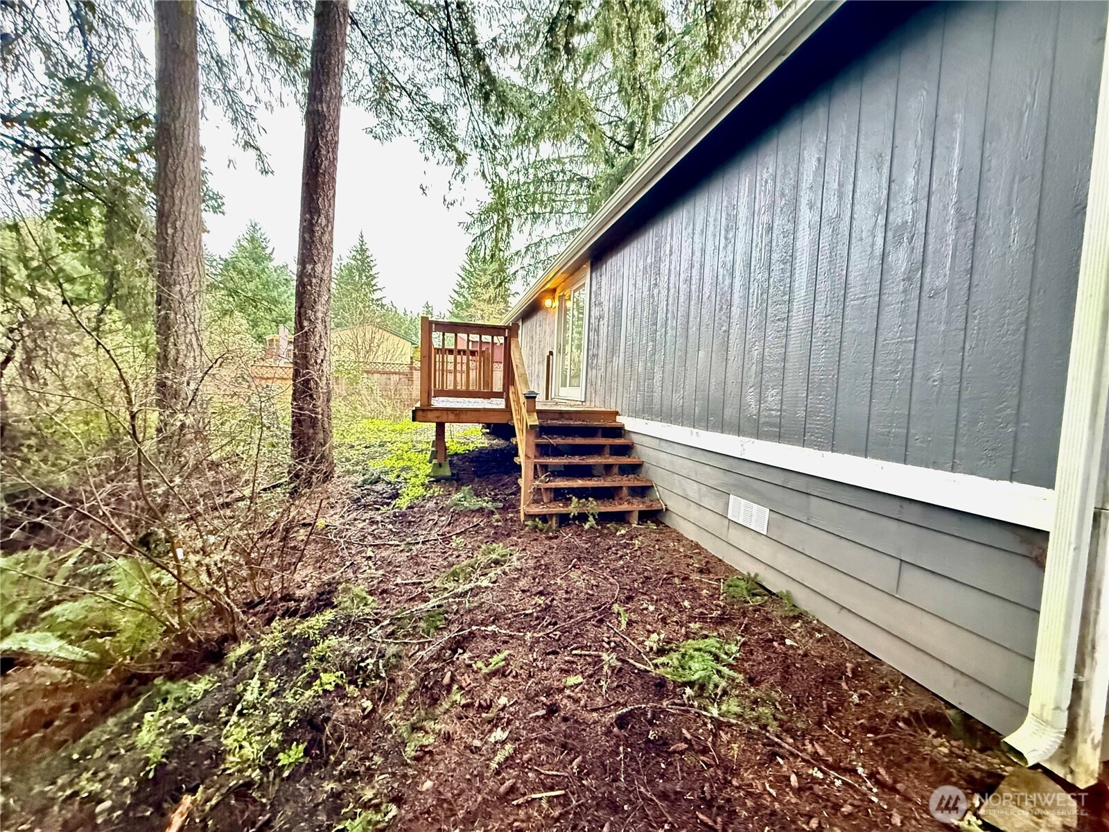 1040 Northeast Larson Boulevard Belfair, WA 98528 - Photo 4 of 18 a backyard of a house with a bench and trees