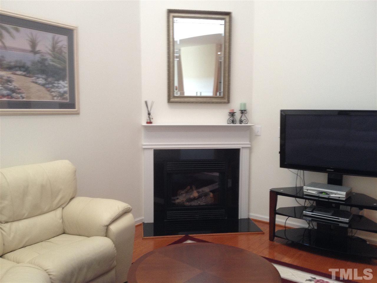 8514 Micollet Court Raleigh, NC 27613 - Photo 4 of 9 a living room with furniture a flat screen tv and a fireplace