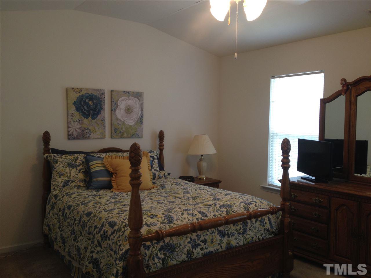 8514 Micollet Court Raleigh, NC 27613 - Photo 6 of 9 a bedroom with a bed and a flat tv screen on the dresser