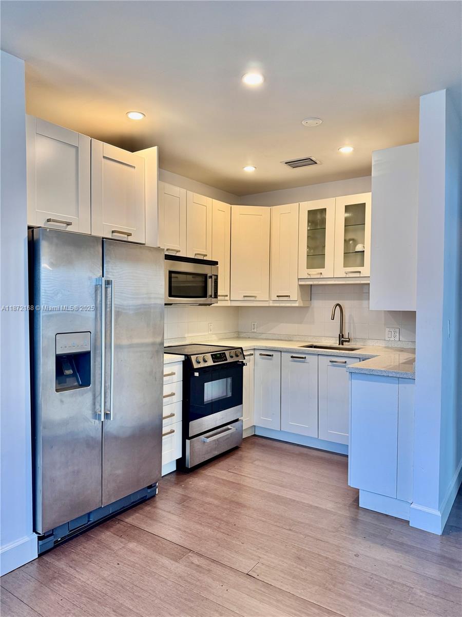1231 13th Street, Unit 2 Miami Beach, FL 33139 - Photo 4 of 8 a large kitchen with stainless steel appliances granite countertop a stove a sink and a refrigerator