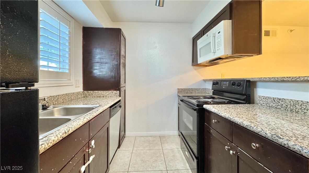 2750 South Durango Drive, Unit 2100 Las Vegas, NV 89117 - Photo 11 of 30 Kitchen featuring black range with electric cooktop, white microwave, dark brown cabinetry, stainless steel dishwasher, and light countertops