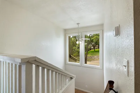an empty room with wooden floor fan and windows