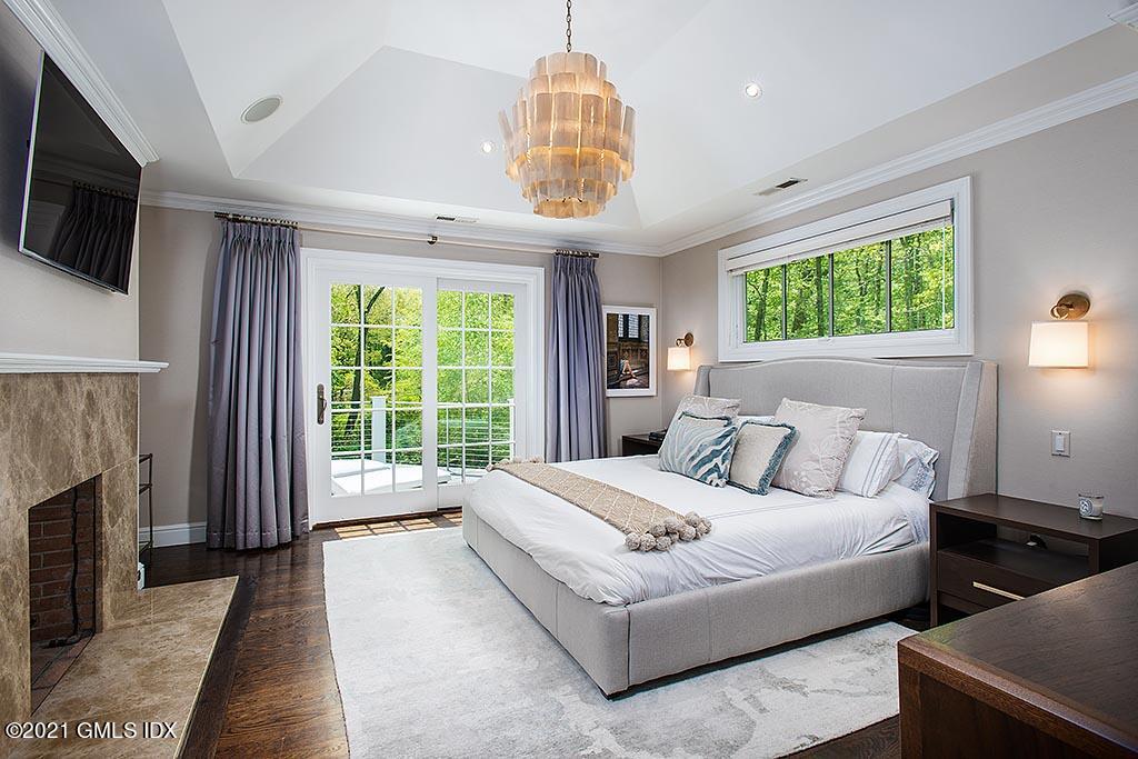 2 Carriage Road Cos Cob, CT 06807 - Photo 12 of 25 a bedroom with a large bed a flat tv screen and a fireplace