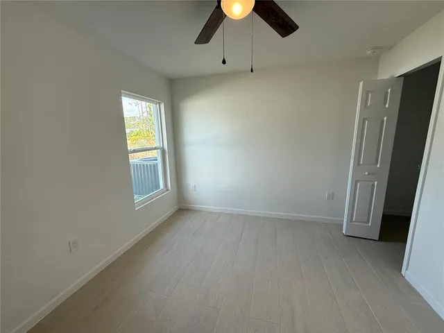 an empty room with a window and a ceiling fan