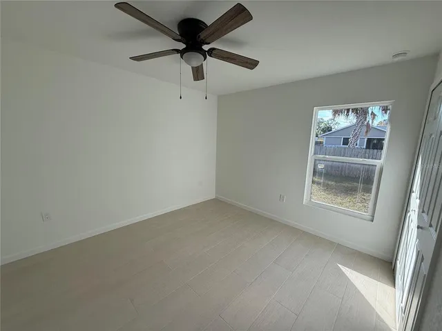 an empty room with a window and a ceiling fan