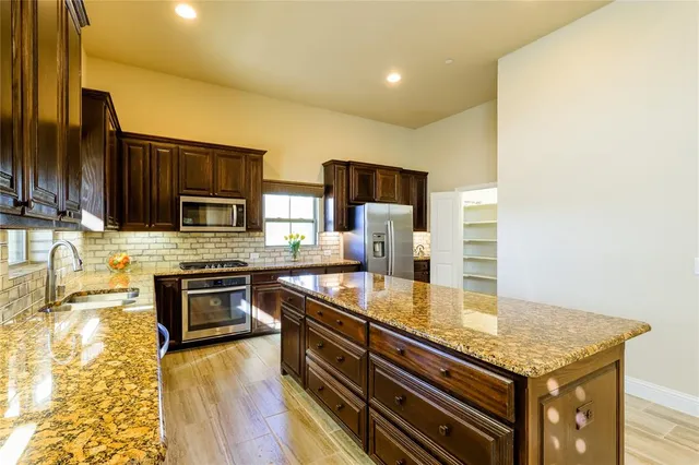 a kitchen with stainless steel appliances granite countertop a stove a sink and a microwave