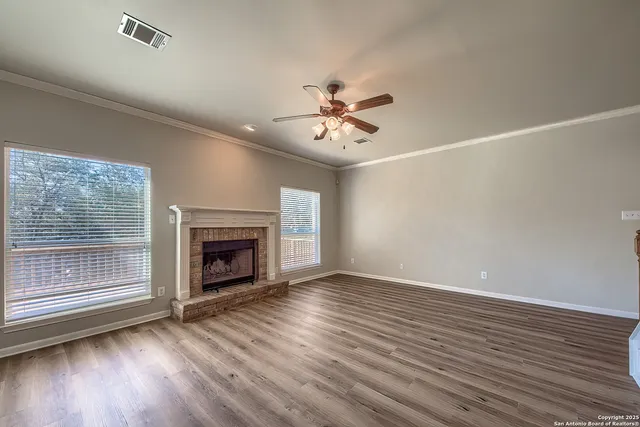 a view of an empty room with wooden floor fireplace and a window