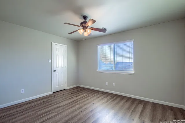 a view of an empty room with wooden floor and a window