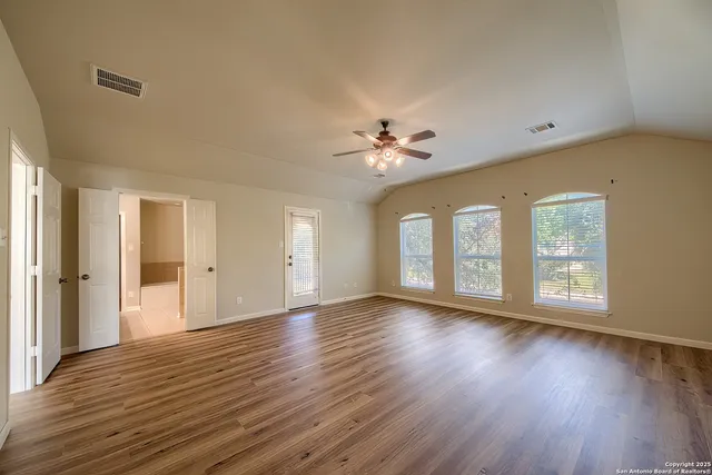 a view of an empty room with a window and wooden floor
