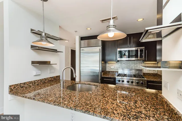 a kitchen with stainless steel appliances granite countertop a sink dishwasher and a stove with wooden floor