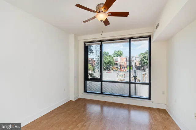 a view of empty room with wooden floor and fan