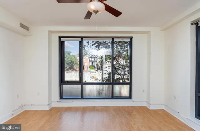 an empty room with wooden floor and windows
