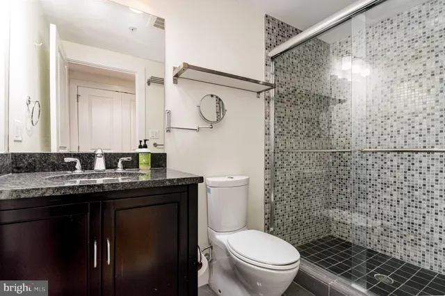 a bathroom with a granite countertop toilet sink vanity and shower
