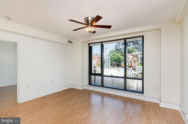 a view of empty room with wooden floor and fan