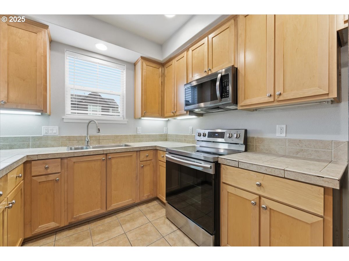 10835 Southwest Huntington Avenue Portland, OR 97223 - Photo 16 of 40 a kitchen with stainless steel appliances granite countertop a sink stove and microwave