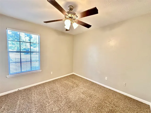 an empty room with a window and a ceiling fan