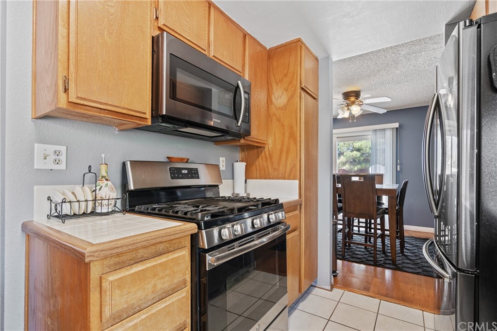 782 De La Luz Circle Perris, CA 92571 - Photo 12 of 25 a kitchen with stainless steel appliances granite countertop a stove top oven a sink dishwasher a dining table and chairs with wooden floor
